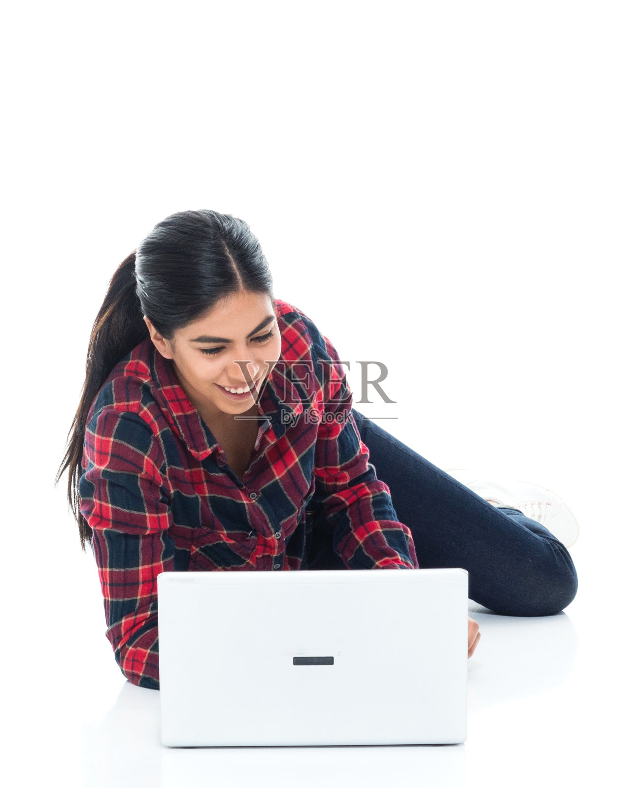 美丽年轻的拉丁美洲女性躺在地板上用笔记本电脑照片摄影图片