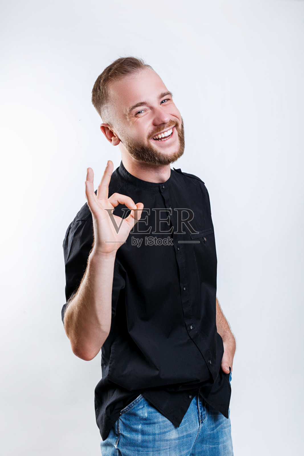 年轻英俊的男子穿着黑色衬衫在灰色背景做ok手势与手微笑照片摄影图片