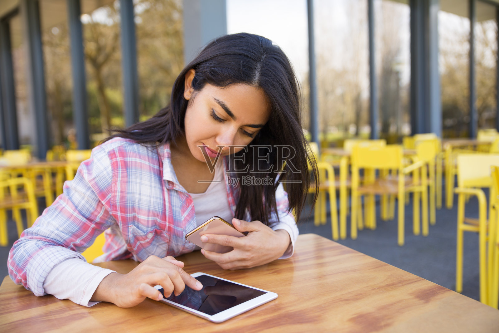 一位严肃的女士在户外咖啡馆使用平板电脑和智能手机照片摄影图片