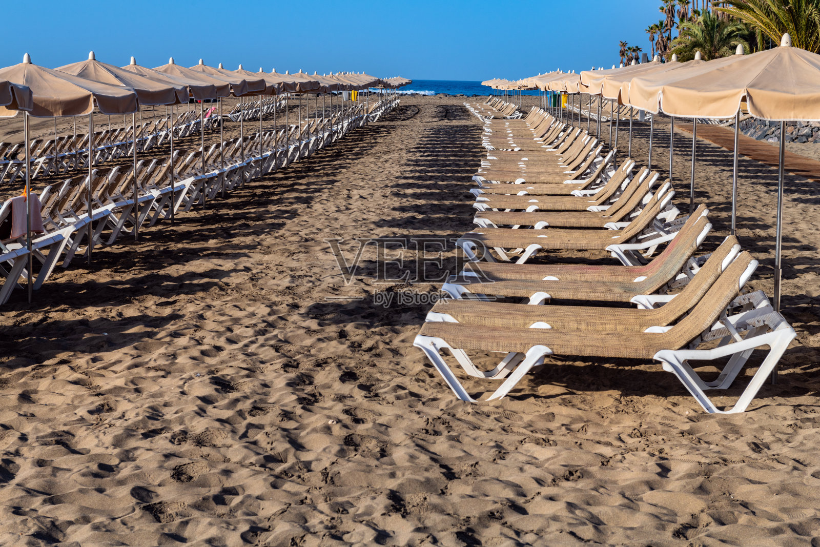 西班牙特内里费岛的洛斯克里斯蒂亚诺斯湾海滩，配有日光浴床和雨伞照片摄影图片