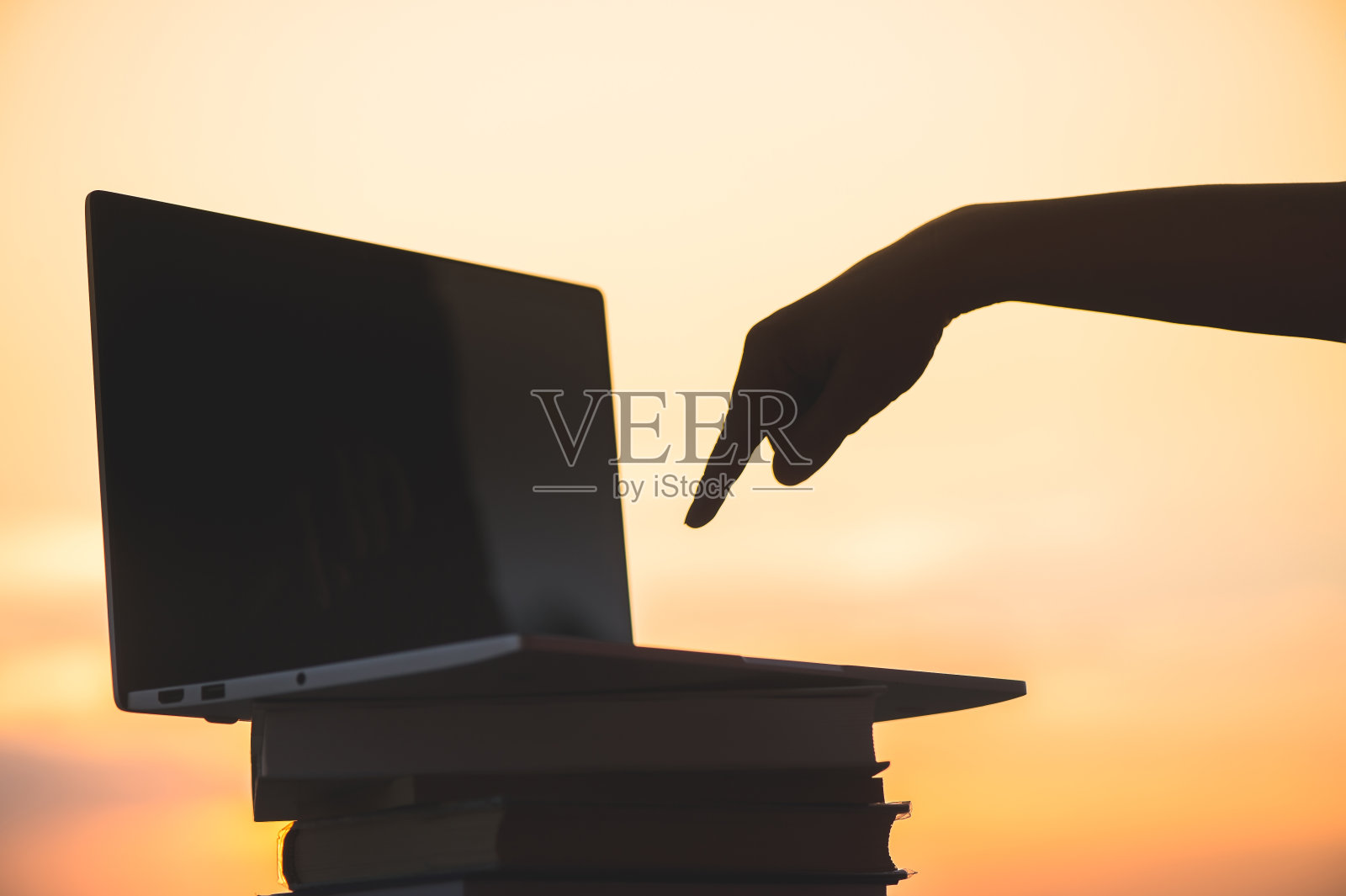 一名女学生在准备大学考试后关闭了她的笔记本电脑，晚上在日落镇的背景。教育的概念照片摄影图片