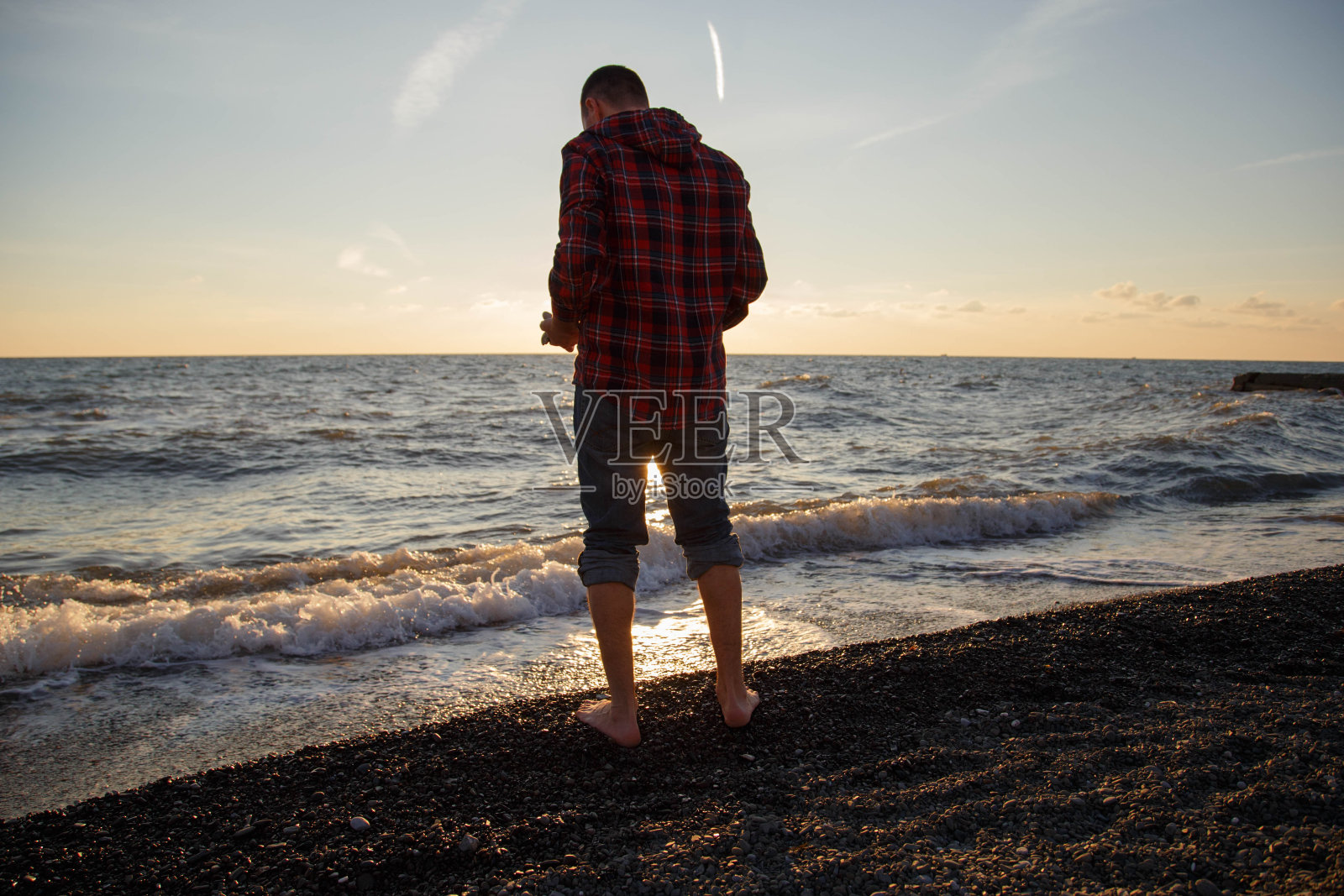 索契，一名男子在黑海上扔石头。照片摄影图片