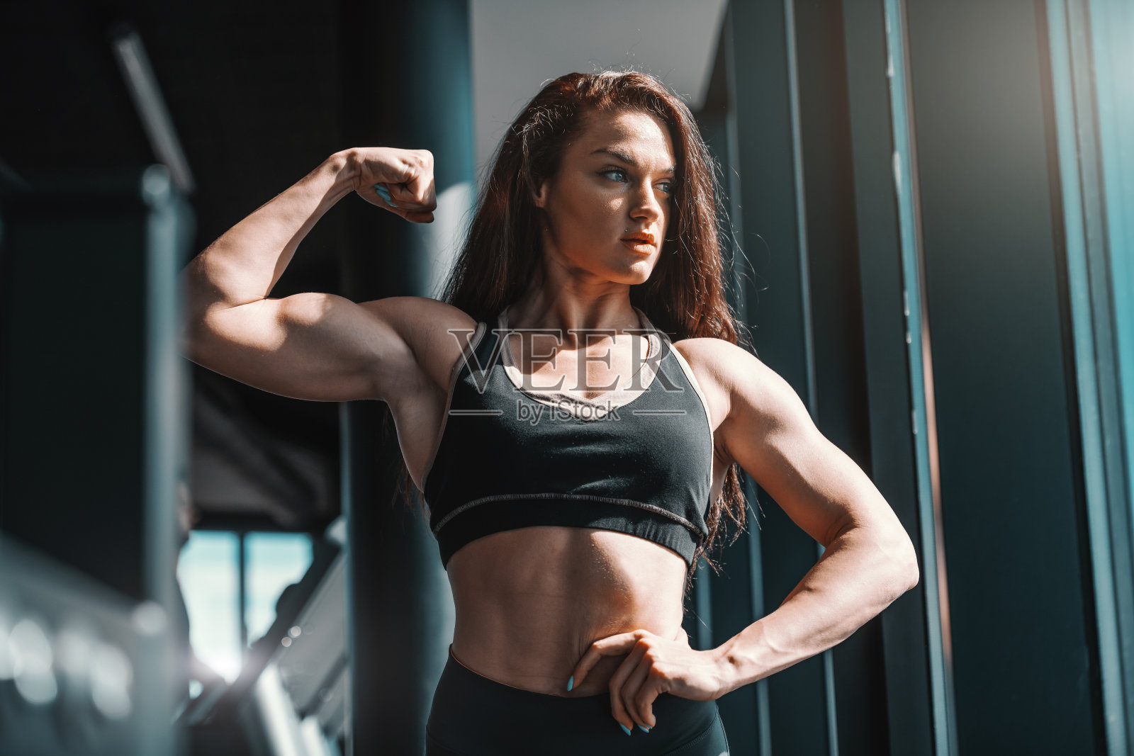 美丽的白人女性健美运动员的肖像在健身房摆姿势和显示肌肉。不要只是希望，要为之努力。照片摄影图片