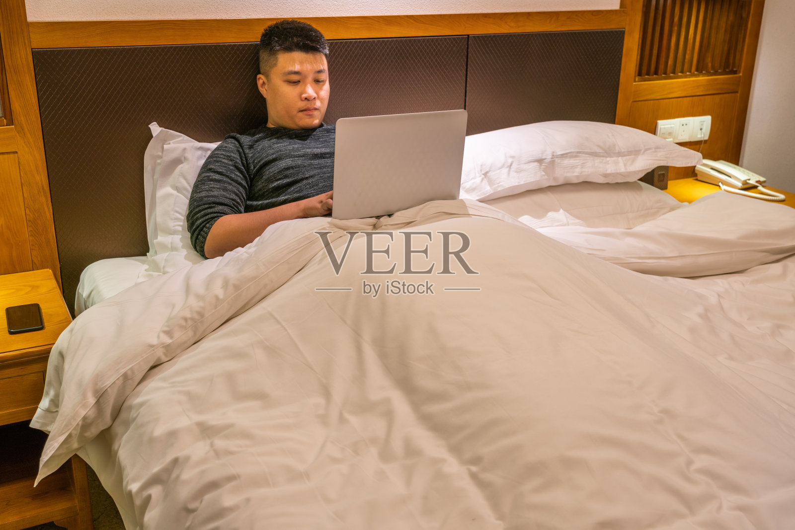 年轻人躺在床上使用笔记本电脑照片摄影图片