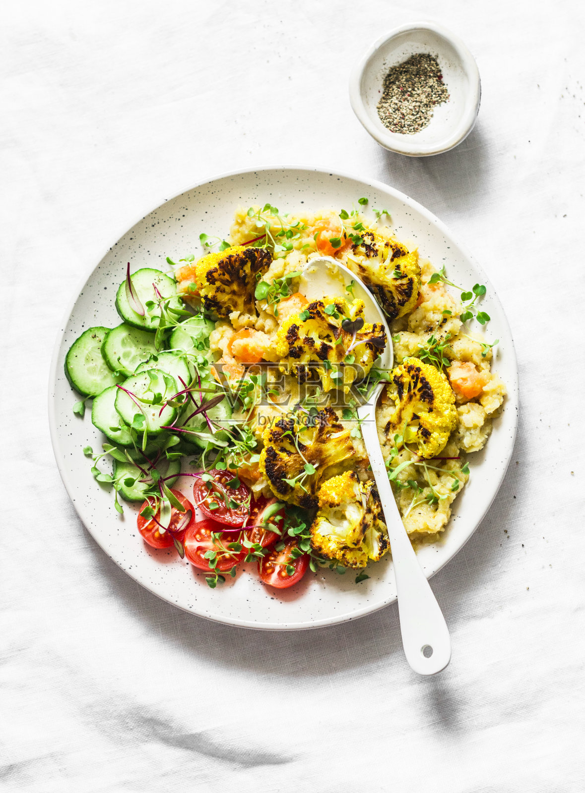 捣碎的黄色南瓜小扁豆，烤的姜黄花椰菜和蔬菜放在一个碗里——在光的背景下，俯视图上是健康的素食照片摄影图片