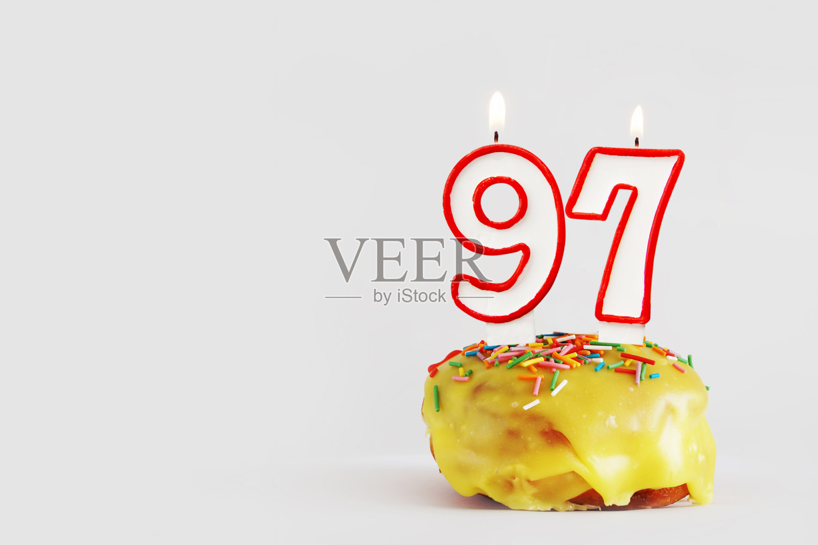 97周年纪念。生日纸杯蛋糕与白色燃烧的蜡烛和红色边框形式的97数字。浅灰色背景与复制空间照片摄影图片