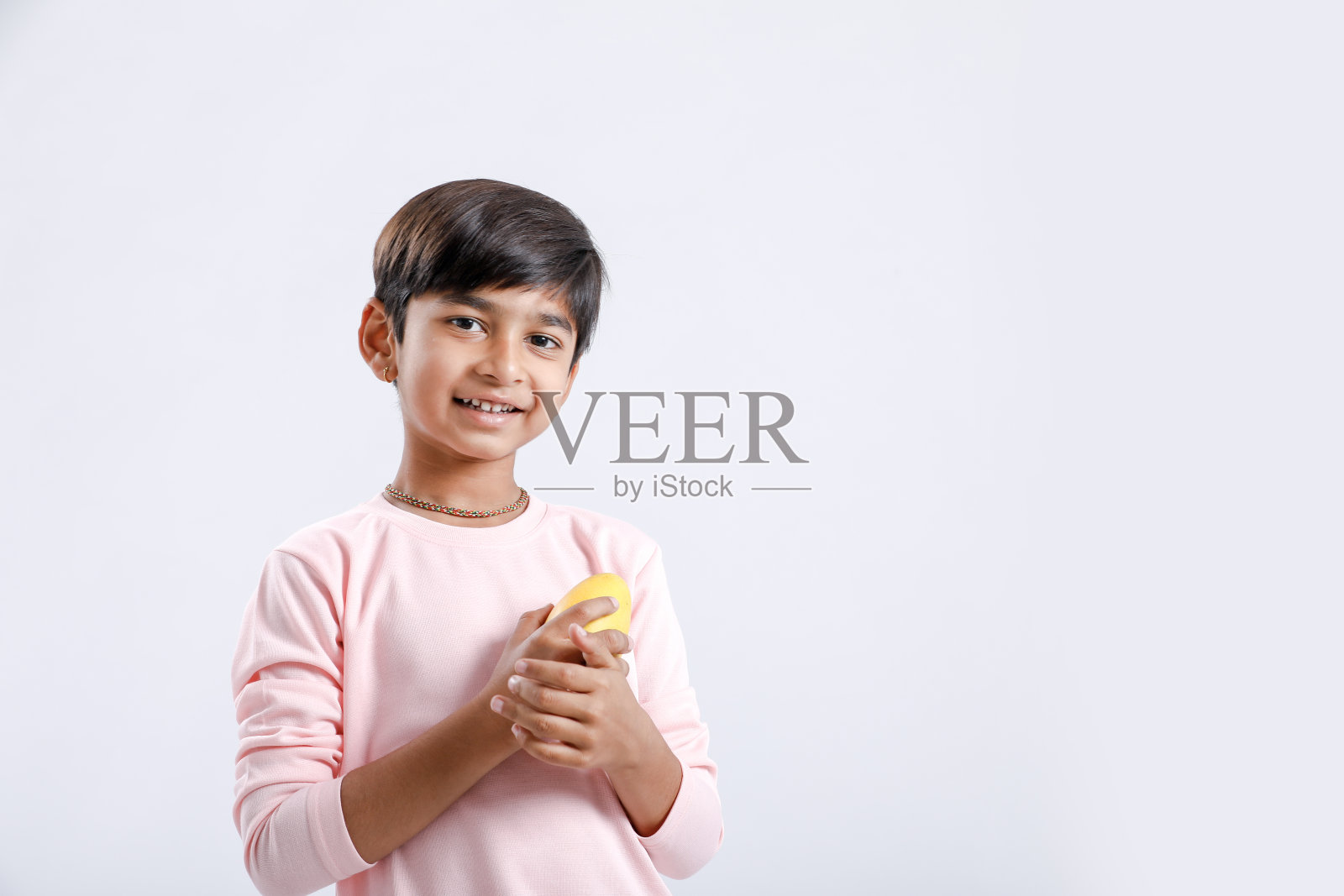 可爱的印度/亚洲小男孩吃芒果，表情多样。在白色背景上隔离照片摄影图片
