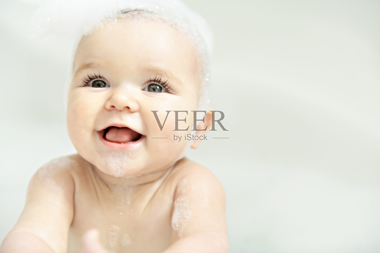 一个女婴在充满泡沫和肥皂泡的浴缸中沐浴照片摄影图片