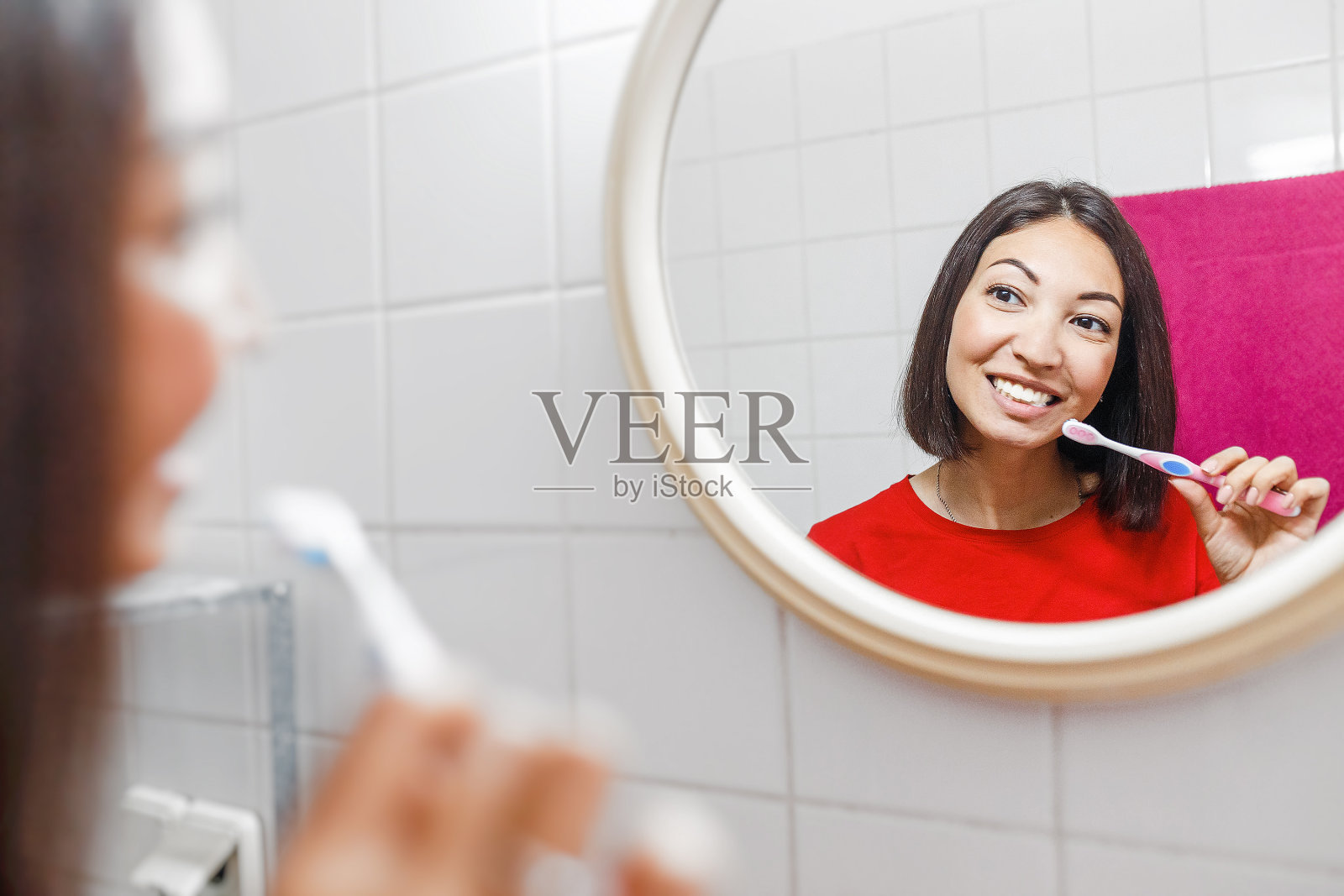 一个亚洲女人在她公寓的浴室里一边刷牙一边照镜子照片摄影图片