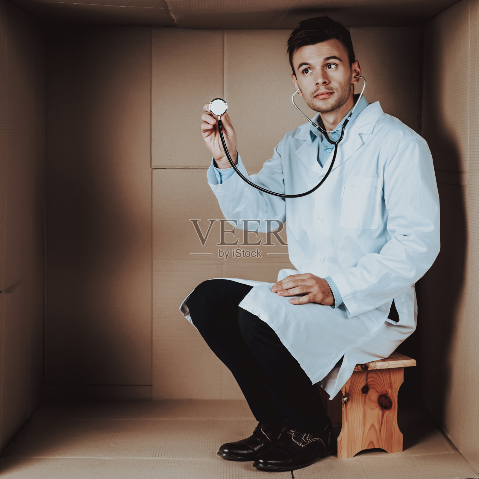 穿着大衣的医生和装在硬纸盒里的听诊器。照片摄影图片