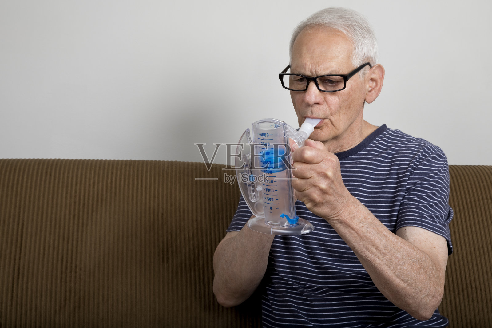老人在家里使用肺活量计照片摄影图片