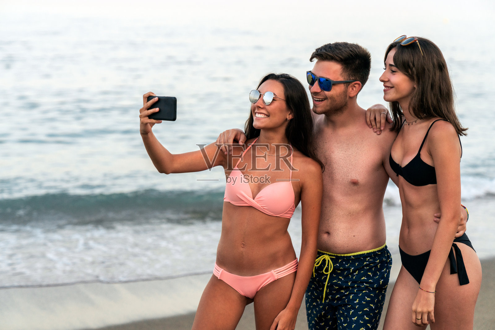 年轻的朋友们一起在海边的沙滩上自拍照片摄影图片