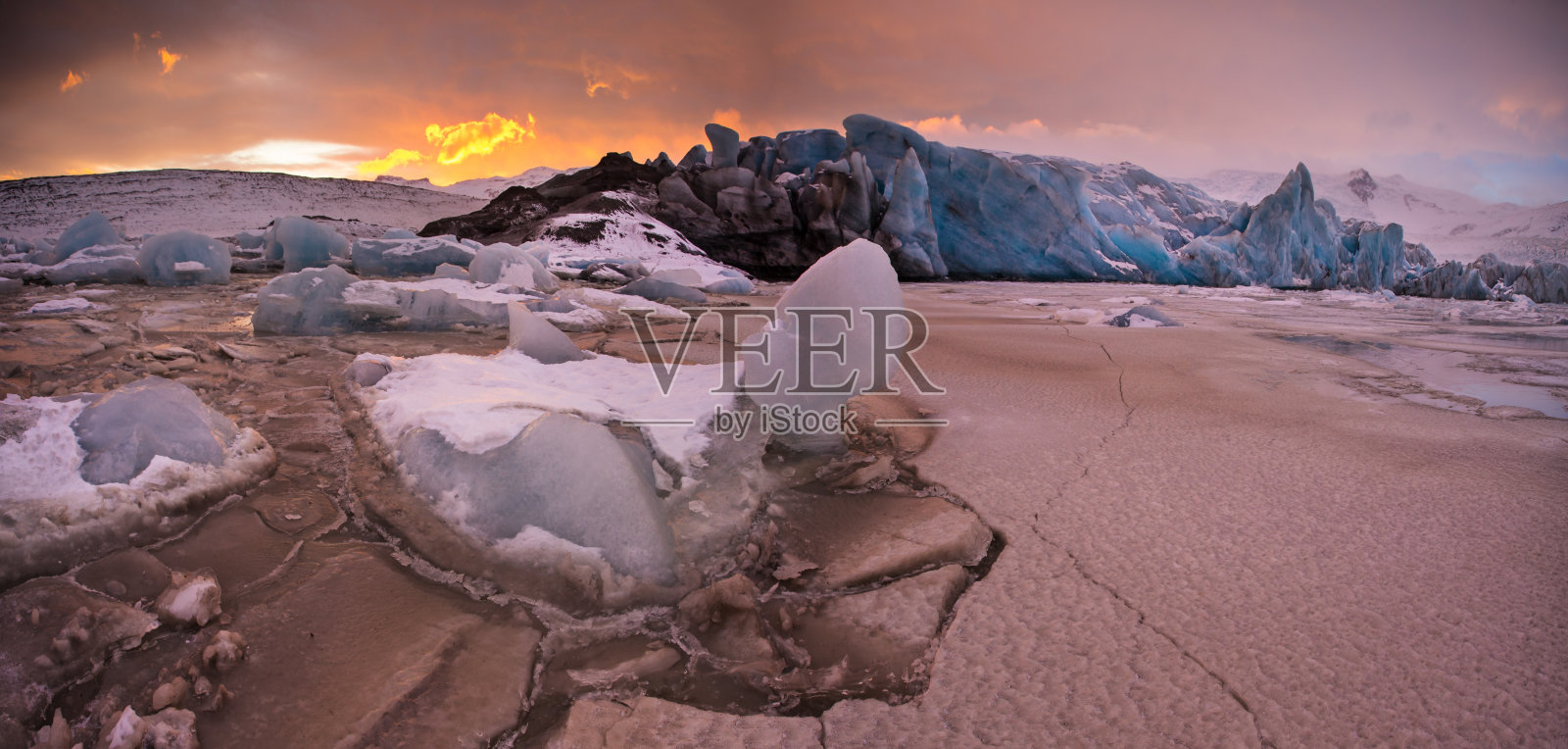 著名的Fjallsarlon冰川和泻湖上的冰山在冰冻的水中游泳，日落。照片摄影图片