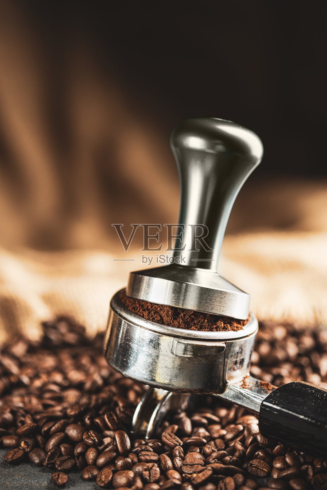 咖啡捣固机，咖啡压榨机是由不锈钢和烘培咖啡豆从咖啡烘培机在黑色背景，工具捣固照片摄影图片