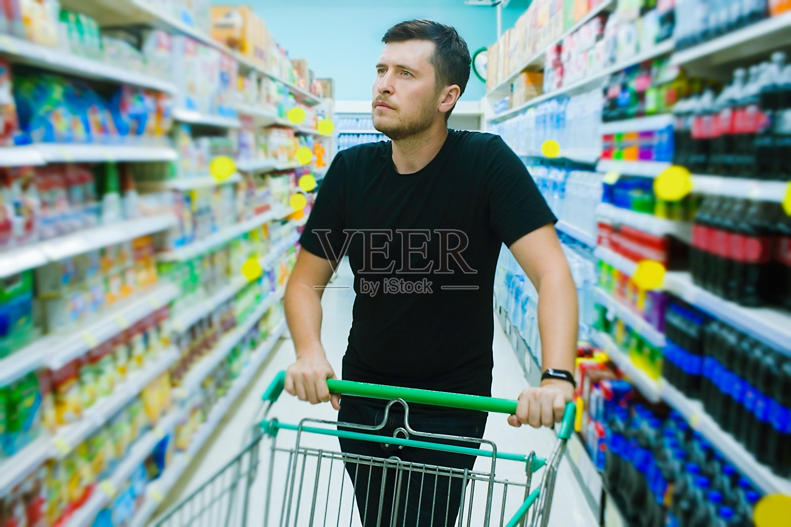 年轻的白人男子在超市的杂货区挑选商品。购物和消费主义的概念。照片摄影图片
