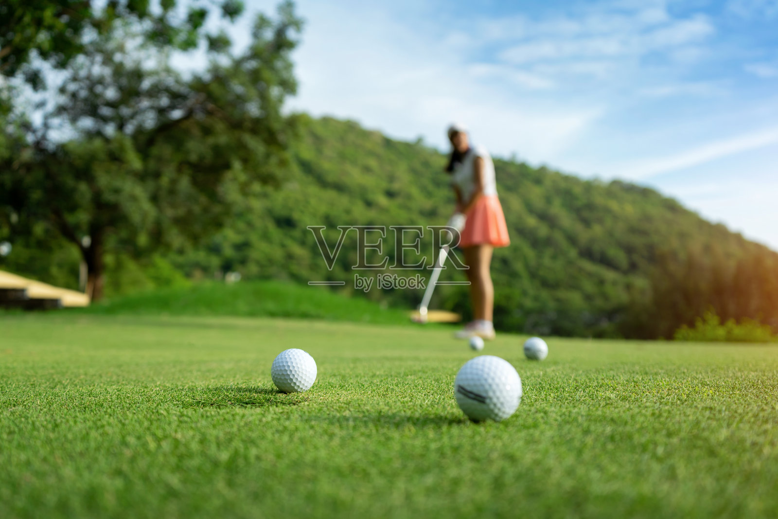 女人驾驶练习高尔夫球或教练在高尔夫球场上的球道在日落照片摄影图片