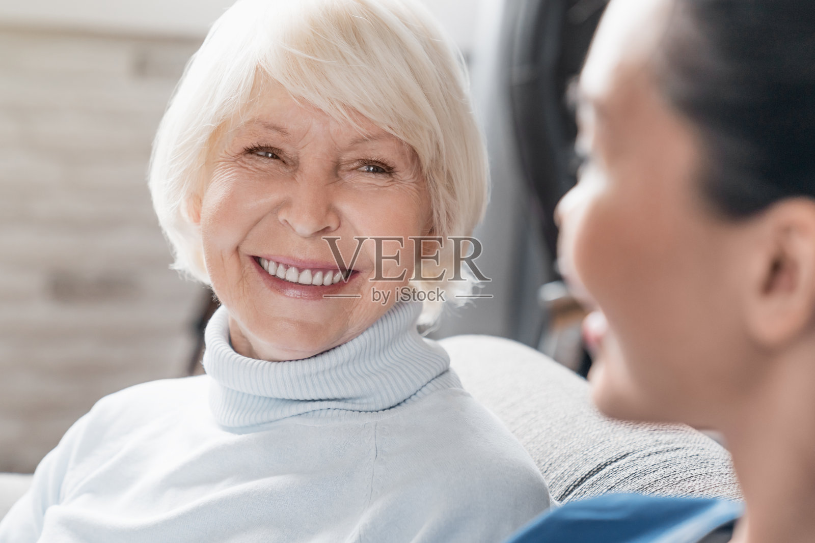 特写的照顾微笑和交谈的老年妇女，而照顾她在家里照片摄影图片