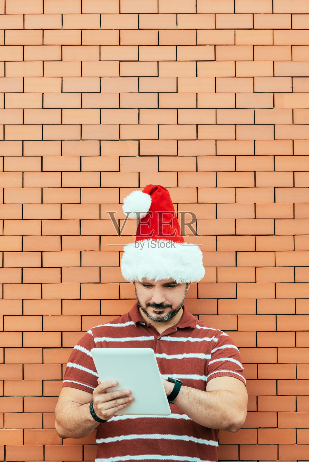 戴着圣诞老人帽的人在用平板电脑照片摄影图片