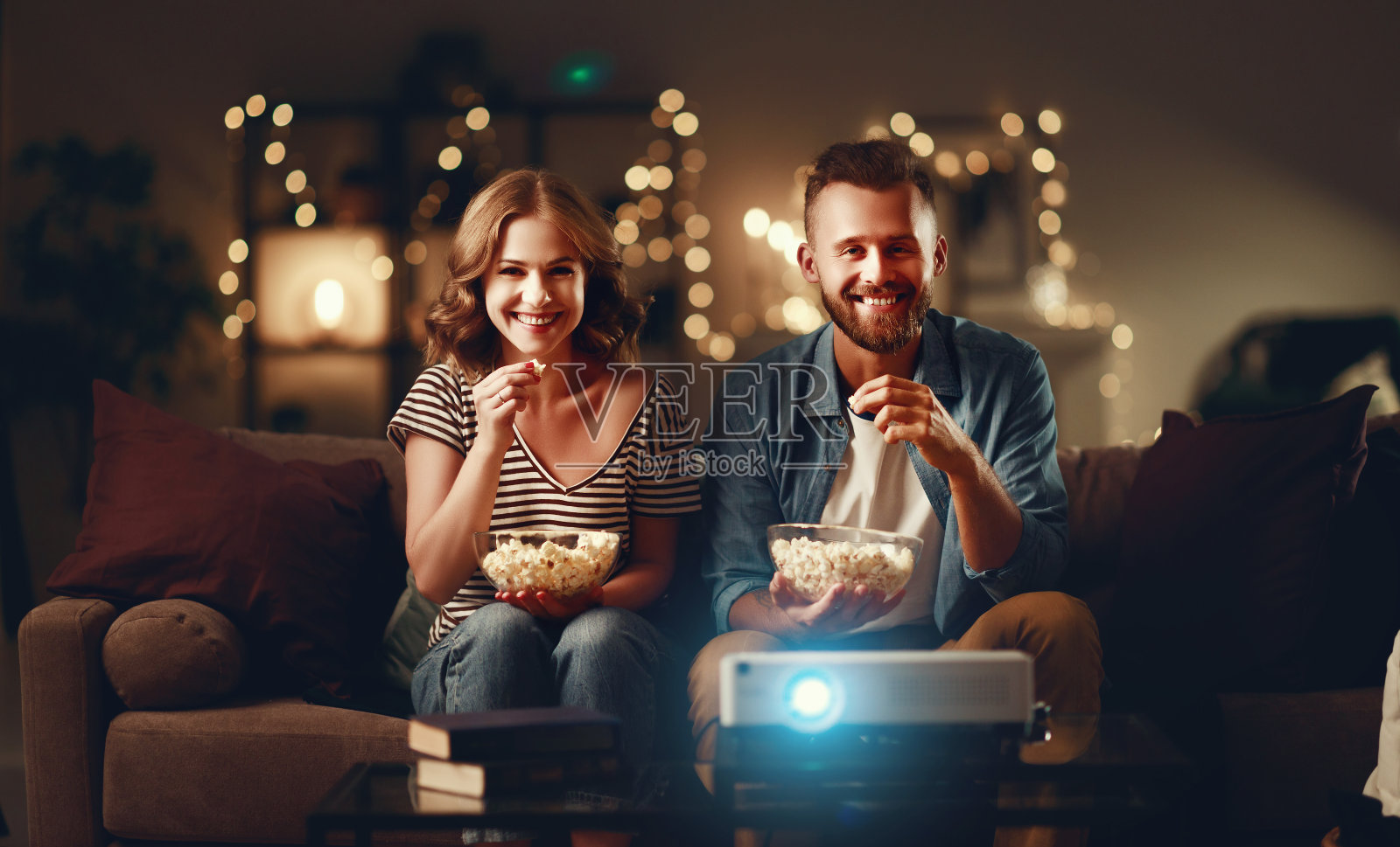 一对家庭夫妇在家里的沙发上看电视放映机照片摄影图片