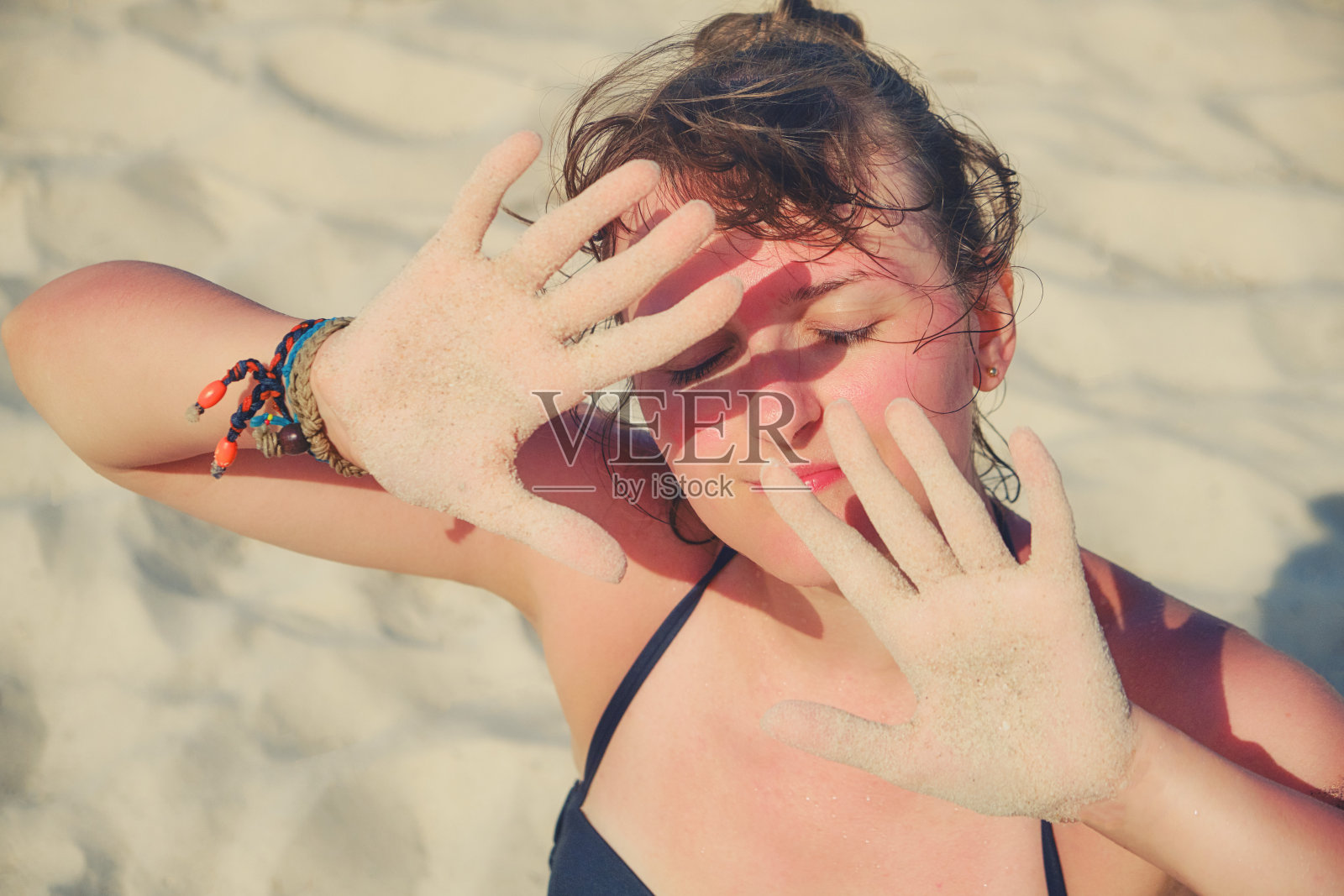 女孩把手放在脸前防晒。照片摄影图片