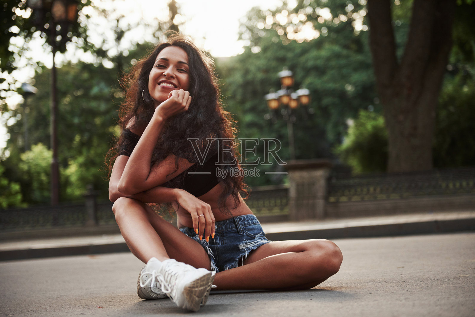 坐在马路上。黑头卷发的美女白天在城里玩得很开心照片摄影图片