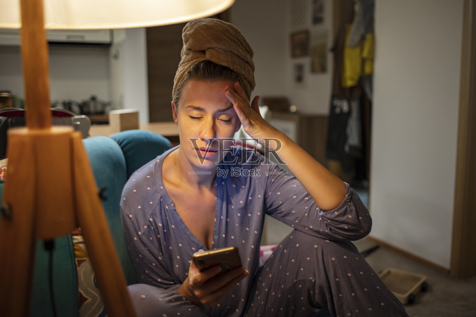 心烦意乱的年轻女子坐在家里的沙发上拿着智能手机照片摄影图片