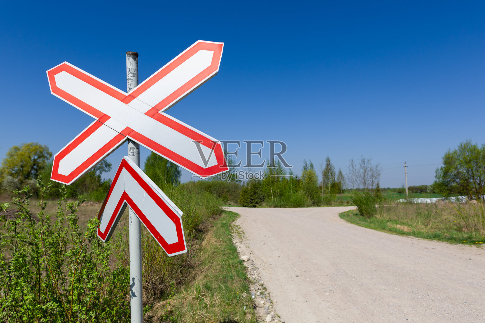 乡村风景中无人看守的铁路道口。红白铁路信号照片摄影图片