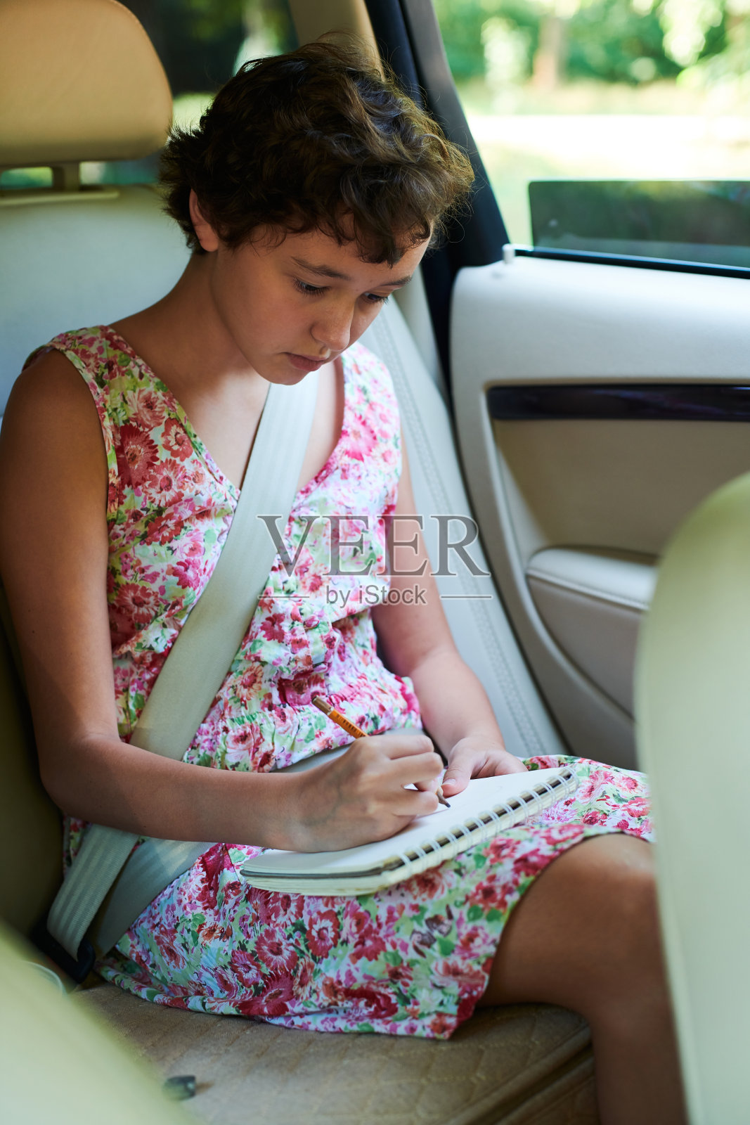 深思熟虑的女孩在汽车后座的速写本上画画照片摄影图片