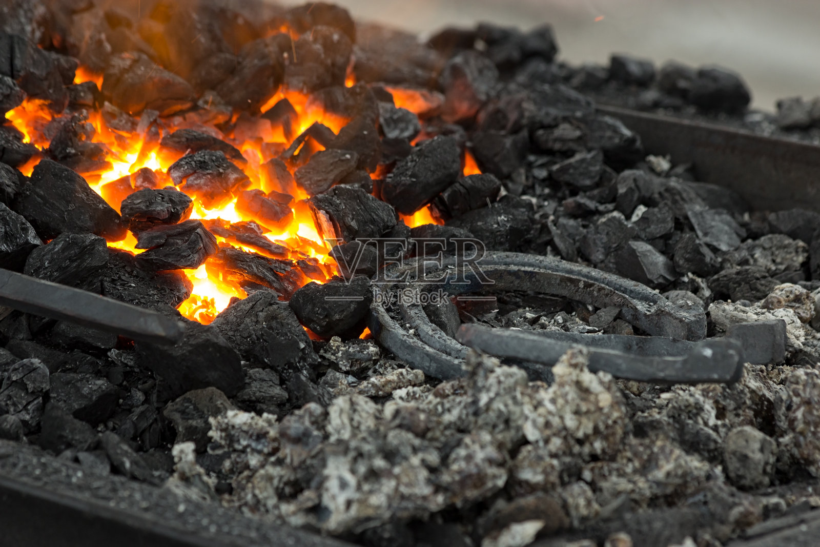 在可移动的锻炉中加热的马蹄铁。余烬在铁炉中燃烧。照片摄影图片