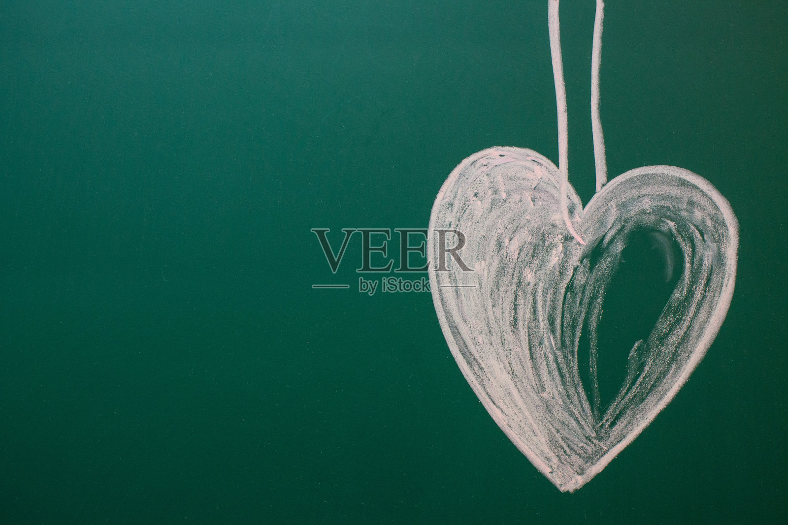 一个用白色粉笔在绿色黑板上画的心照片摄影图片