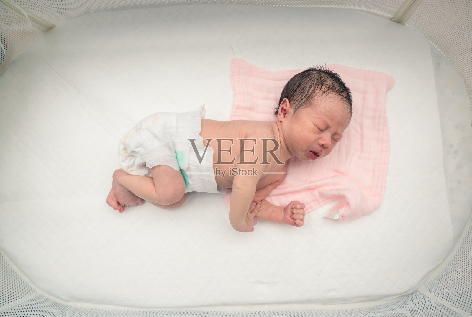 在白色的婴儿床里熟睡的新生婴儿照片摄影图片