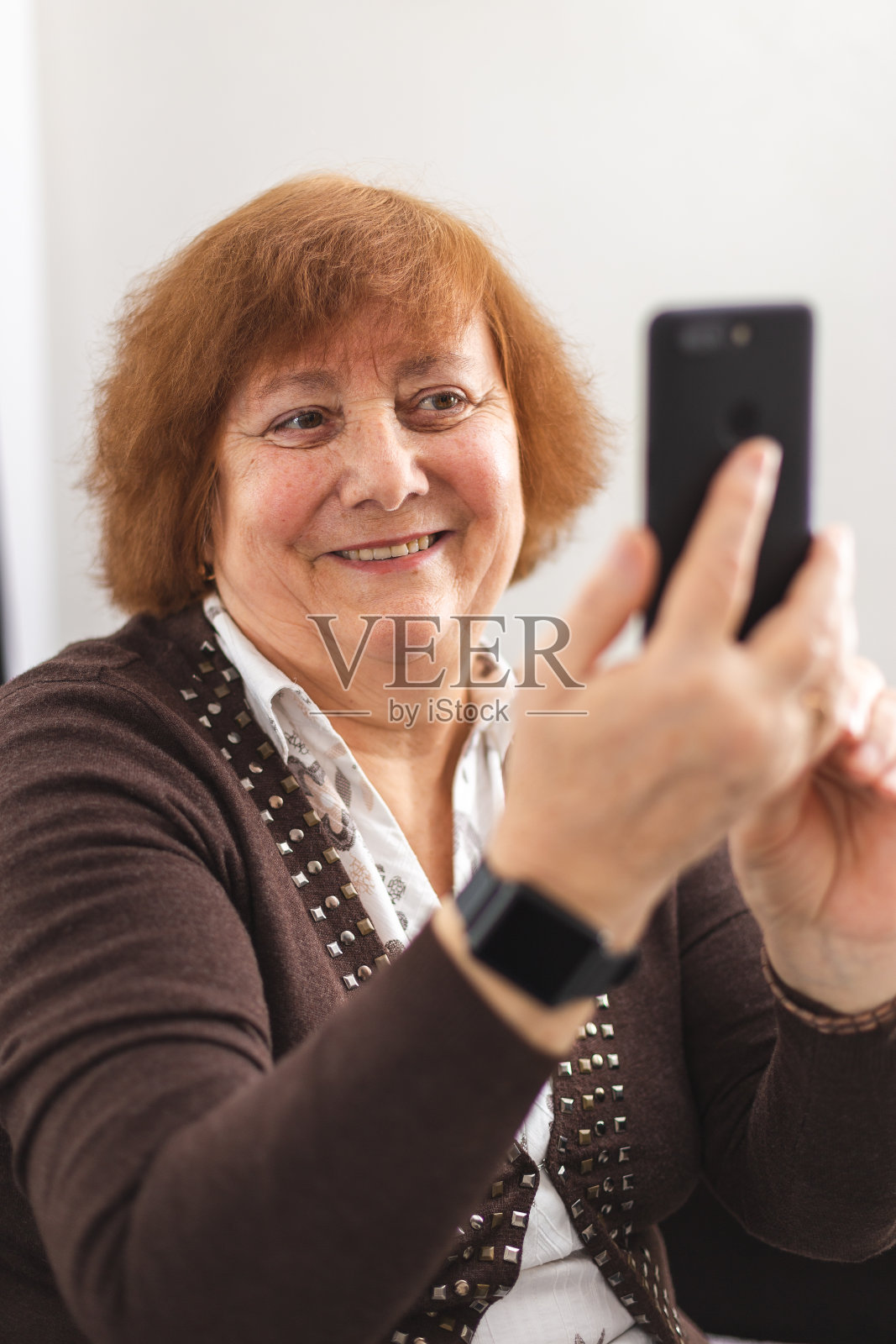 一个老女人用她的智能手机打视频电话。老妇人使用新技术照片摄影图片