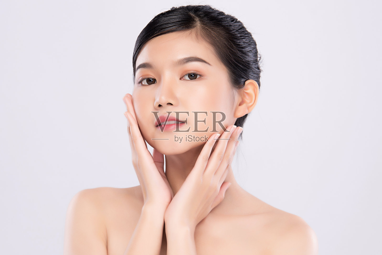 美丽年轻的亚洲女人与清洁新鲜的皮肤。面部护理，面部护理，浅灰色背景，美容和化妆品的概念照片摄影图片