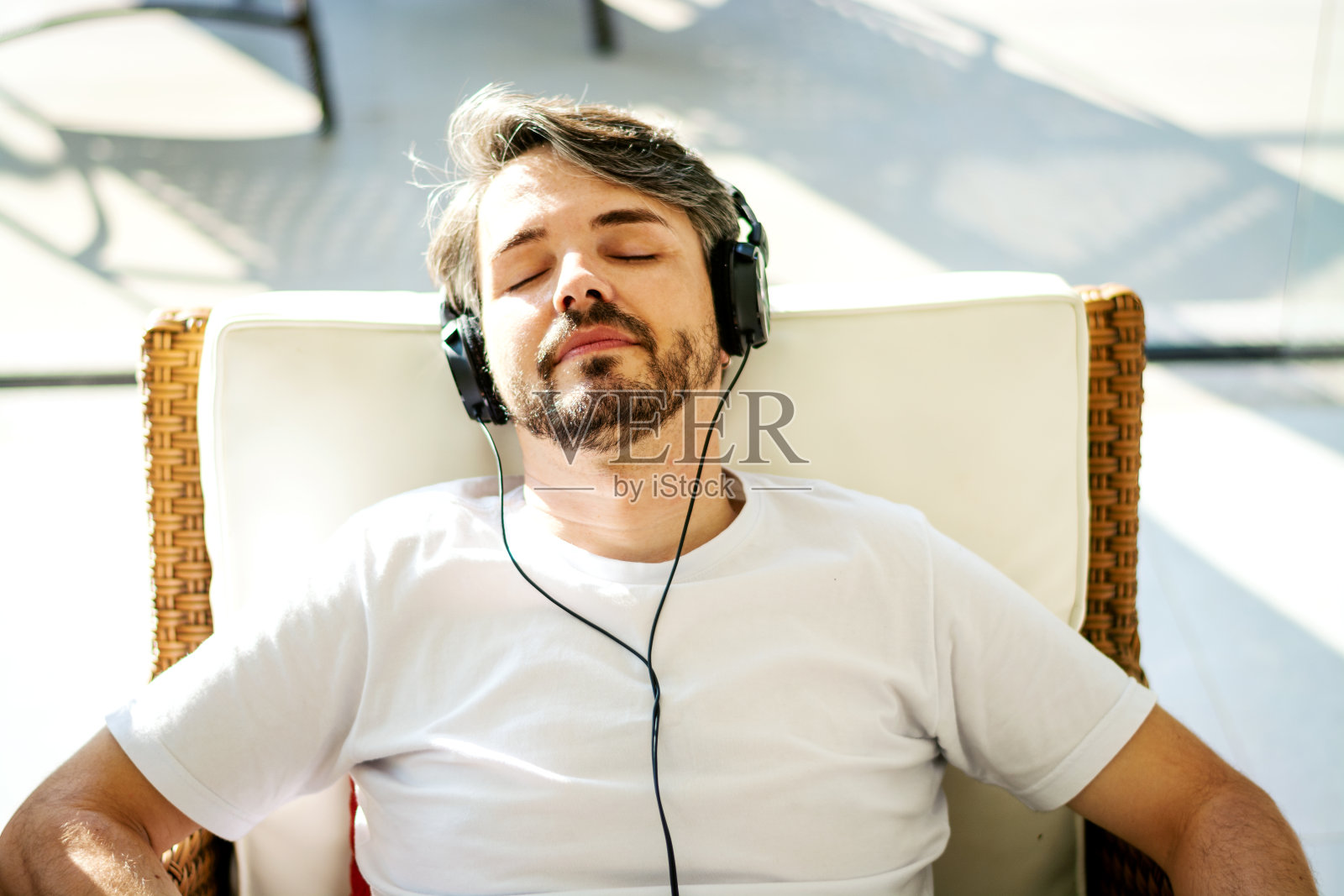 男人戴着耳机听音乐，躺在沙发上休息照片摄影图片