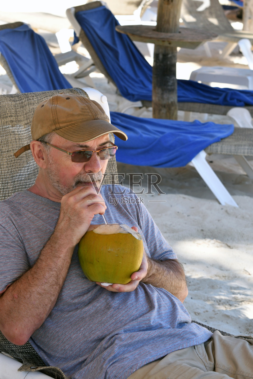 在加勒比海滩上用吸管喝椰奶的老人照片摄影图片