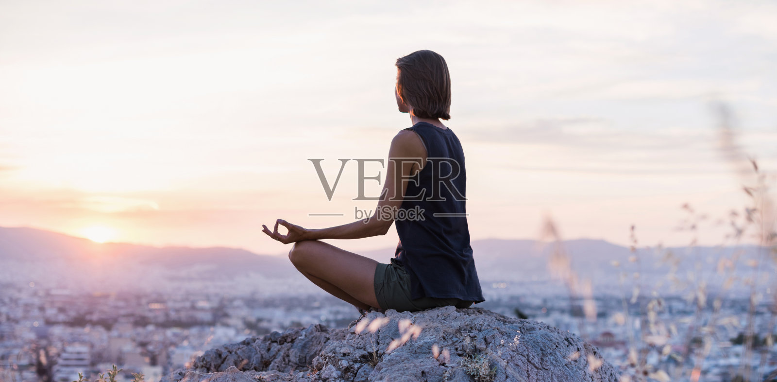 日落时分，一名女子在城市里练习瑜伽。冥想与和谐理念照片摄影图片