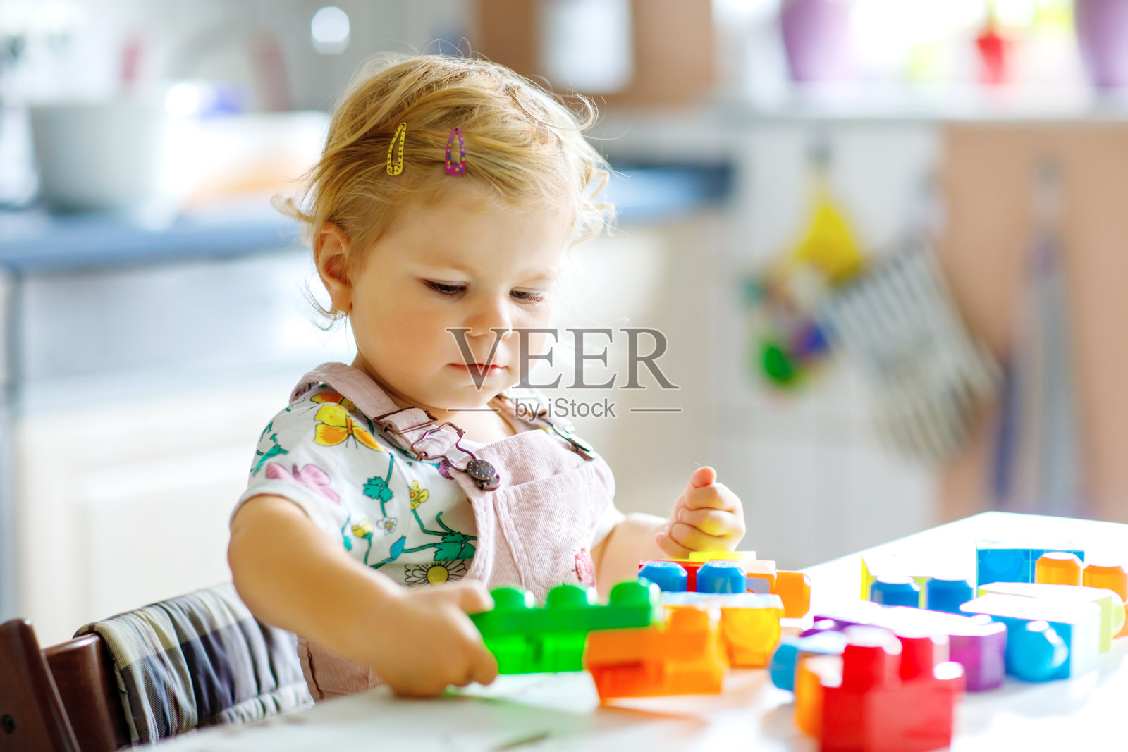 可爱的蹒跚学步的女孩在幼儿园玩教育玩具。快乐健康的孩子有乐趣与彩色不同的塑料块在家里。可爱的宝宝学习创造和建设。照片摄影图片