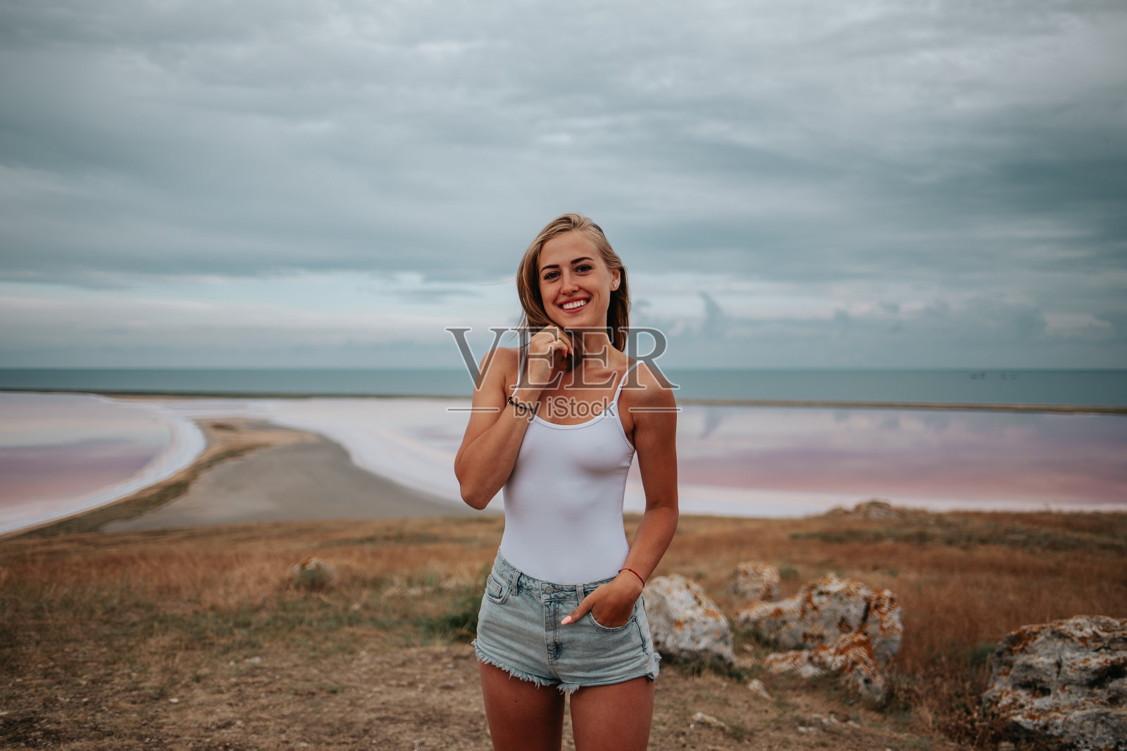 一个穿着白色紧身衣的美丽女孩的肖像在粉红色的盐湖照片摄影图片