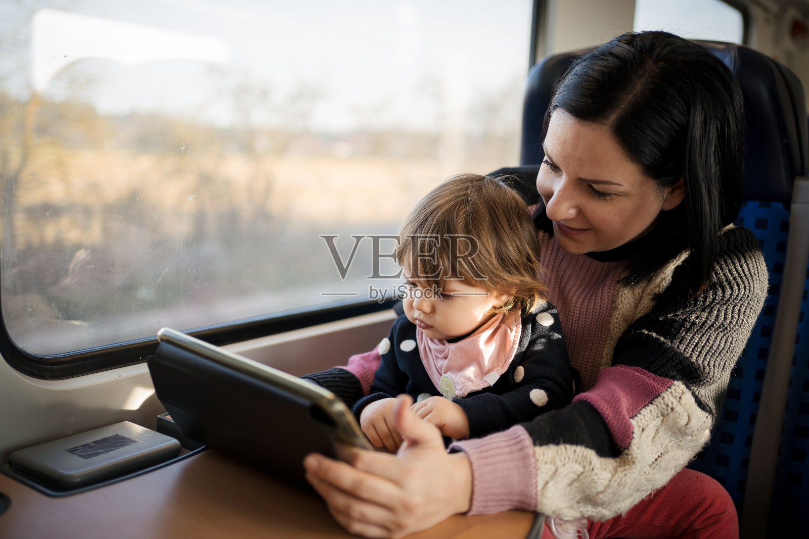 一位年轻的母亲带着她的孩子乘火车旅行，穿过美丽的风景照片摄影图片