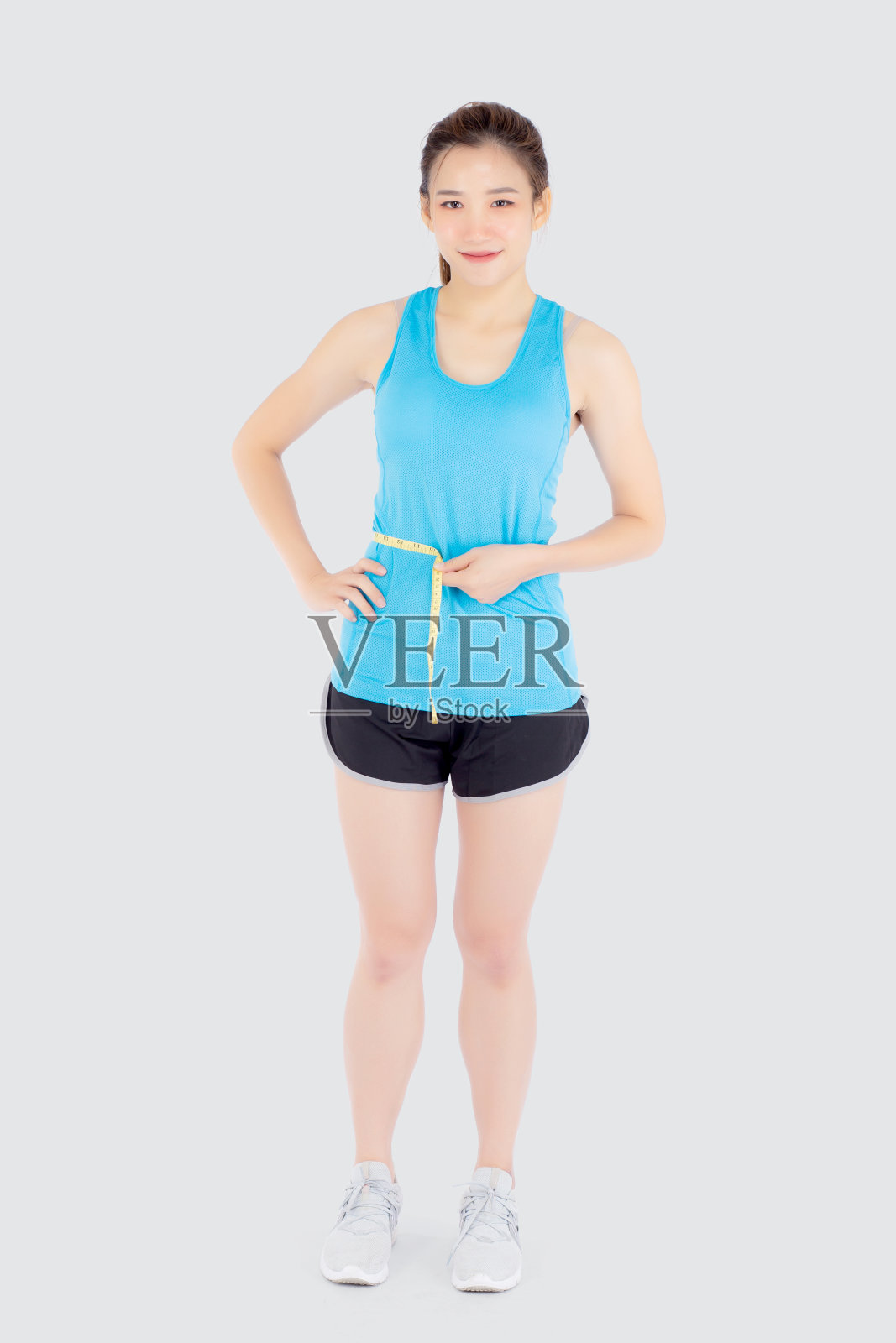 美丽苗条的年轻亚洲女子测量尺瘦腰穿制服健身孤立的白色背景，亚洲女孩减肥与饮食运动和锻炼健康和保健身体。照片摄影图片
