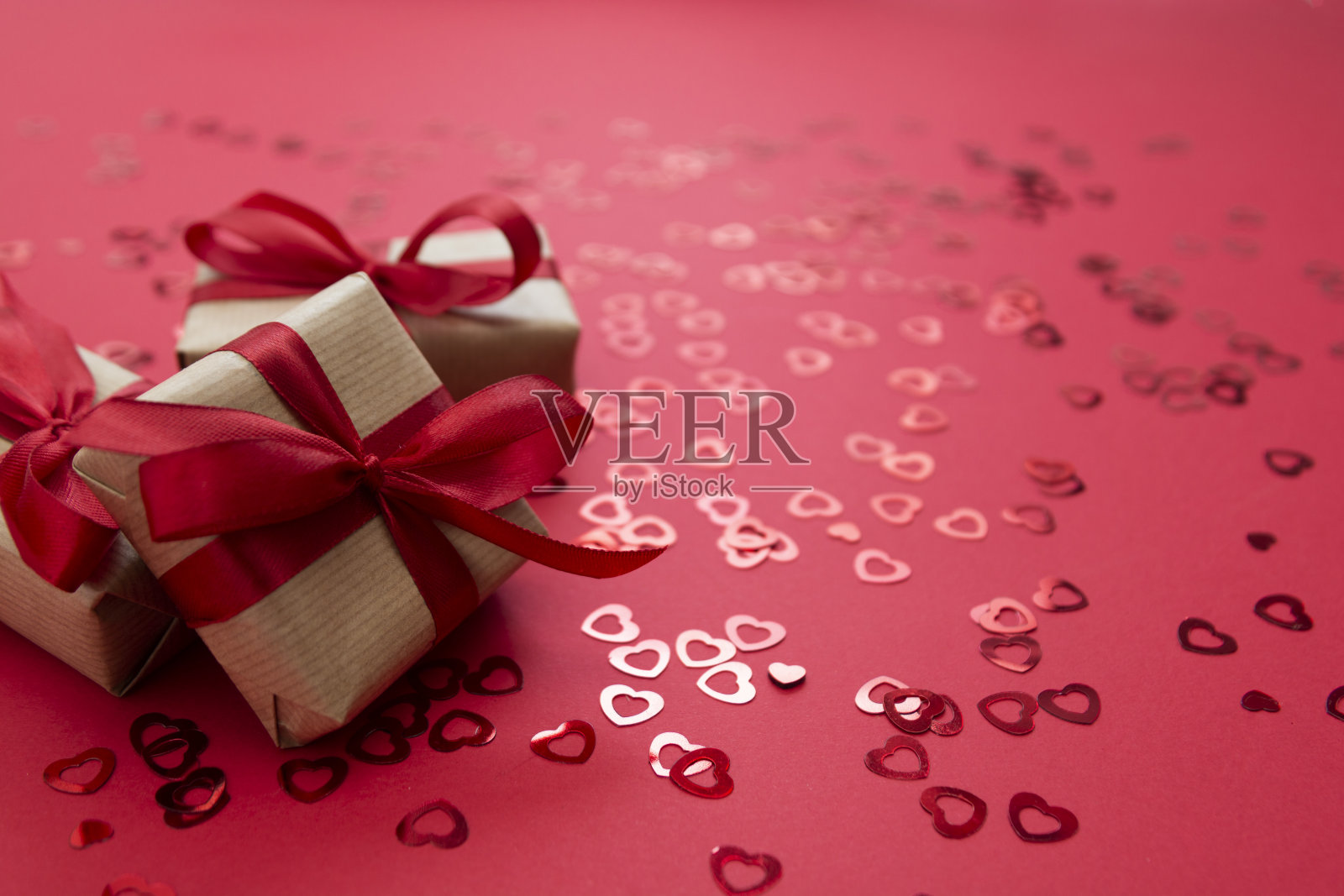爱情，情人节的背景。礼盒包装牛皮纸和红色弓孤立在红色背景。照片摄影图片