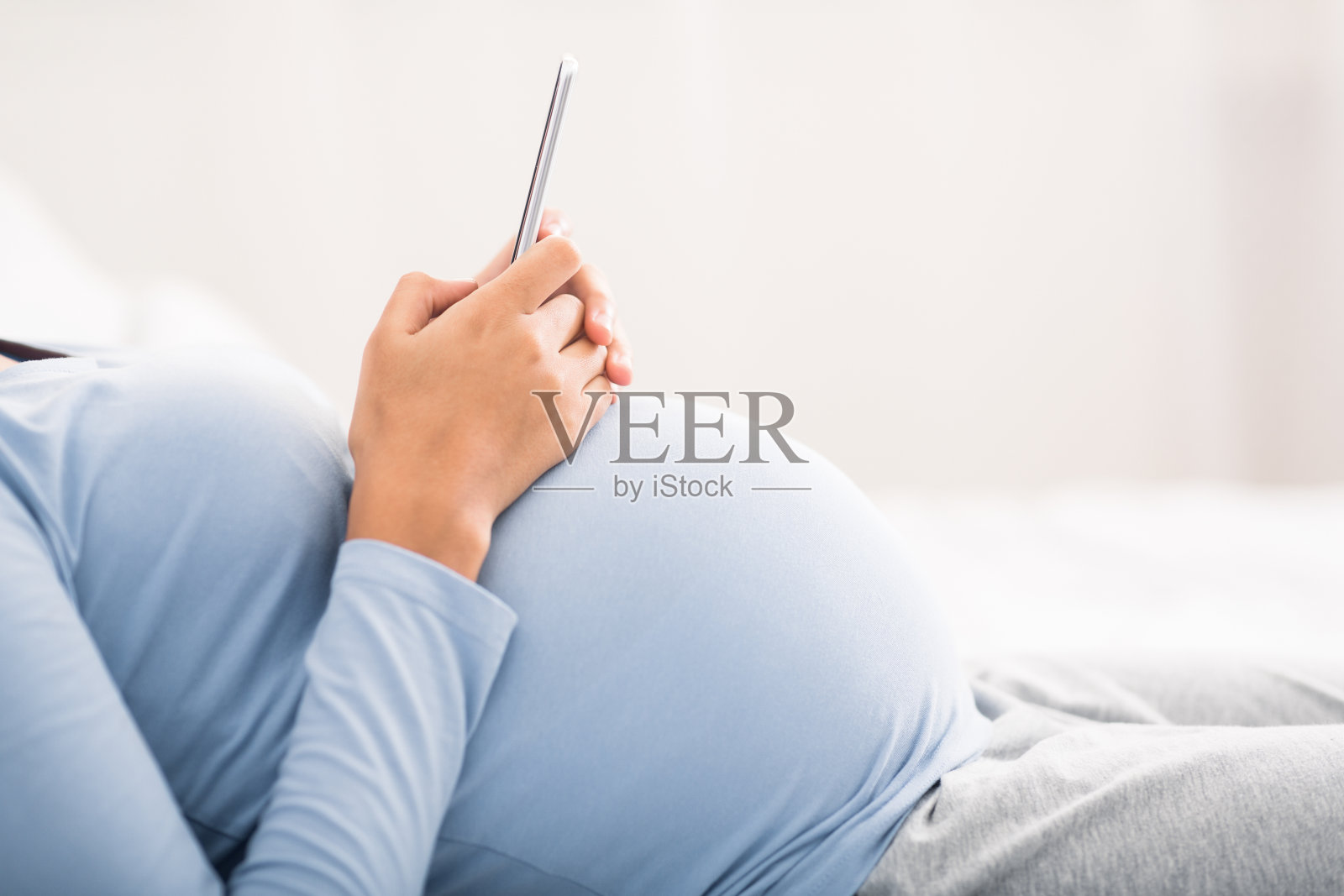 在卧室里使用智能手机的孕妇照片摄影图片