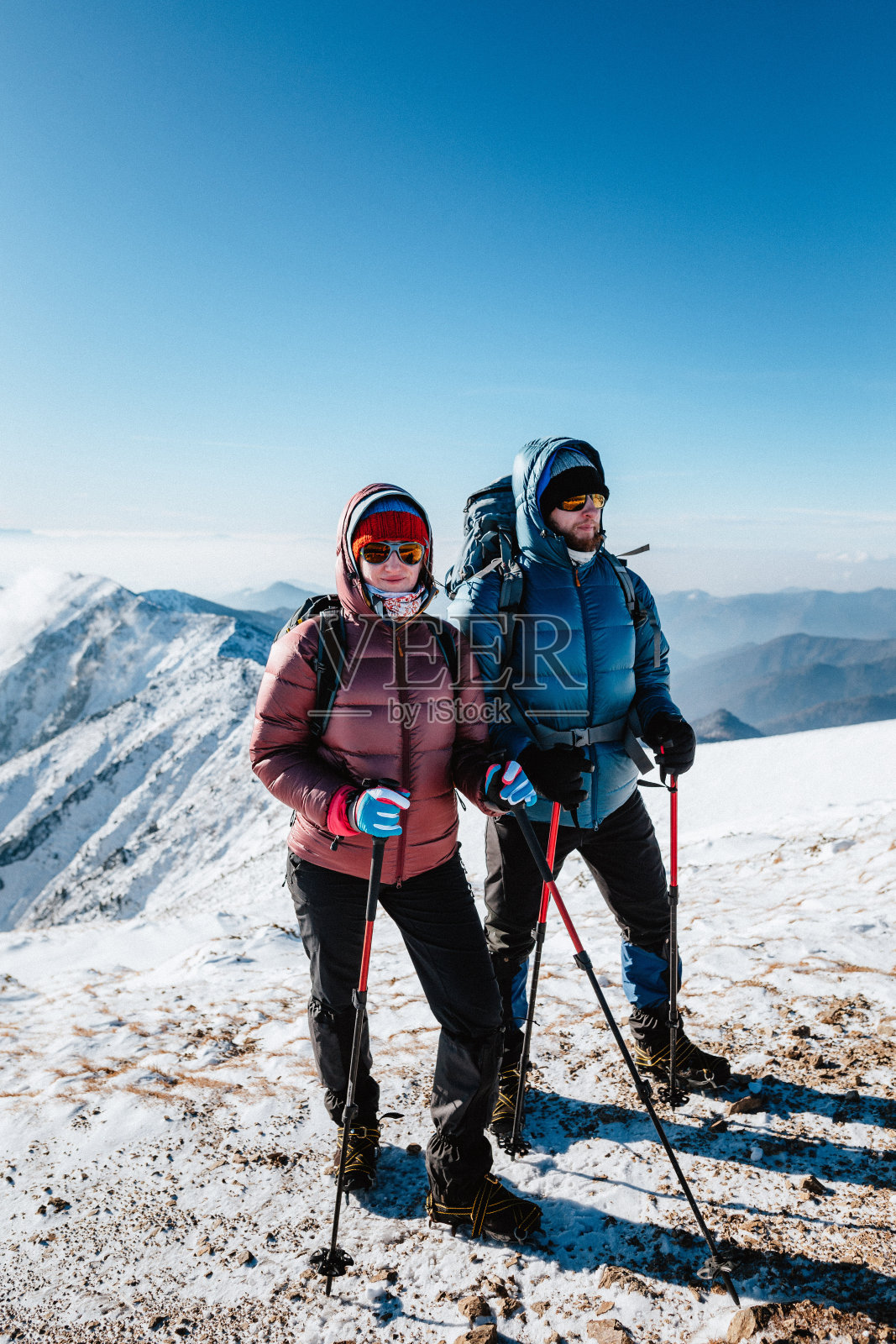 几名登山者在阳光明媚的冬天站在山上照片摄影图片