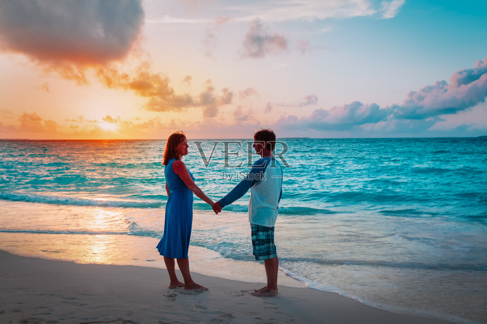 一对浪漫的情侣在日落海滩上牵着手照片摄影图片