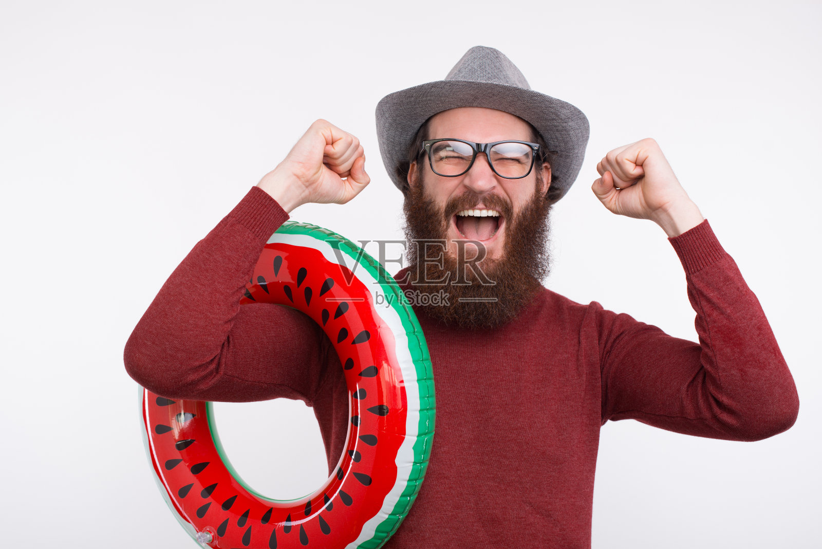 一名戴着眼镜和帽子的大胡子男子举着西瓜游了一圈。照片摄影图片