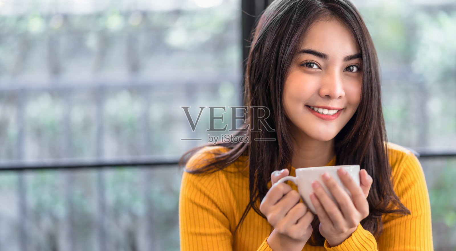 亚洲年轻女性拿着一杯咖啡在现代咖啡店照片摄影图片