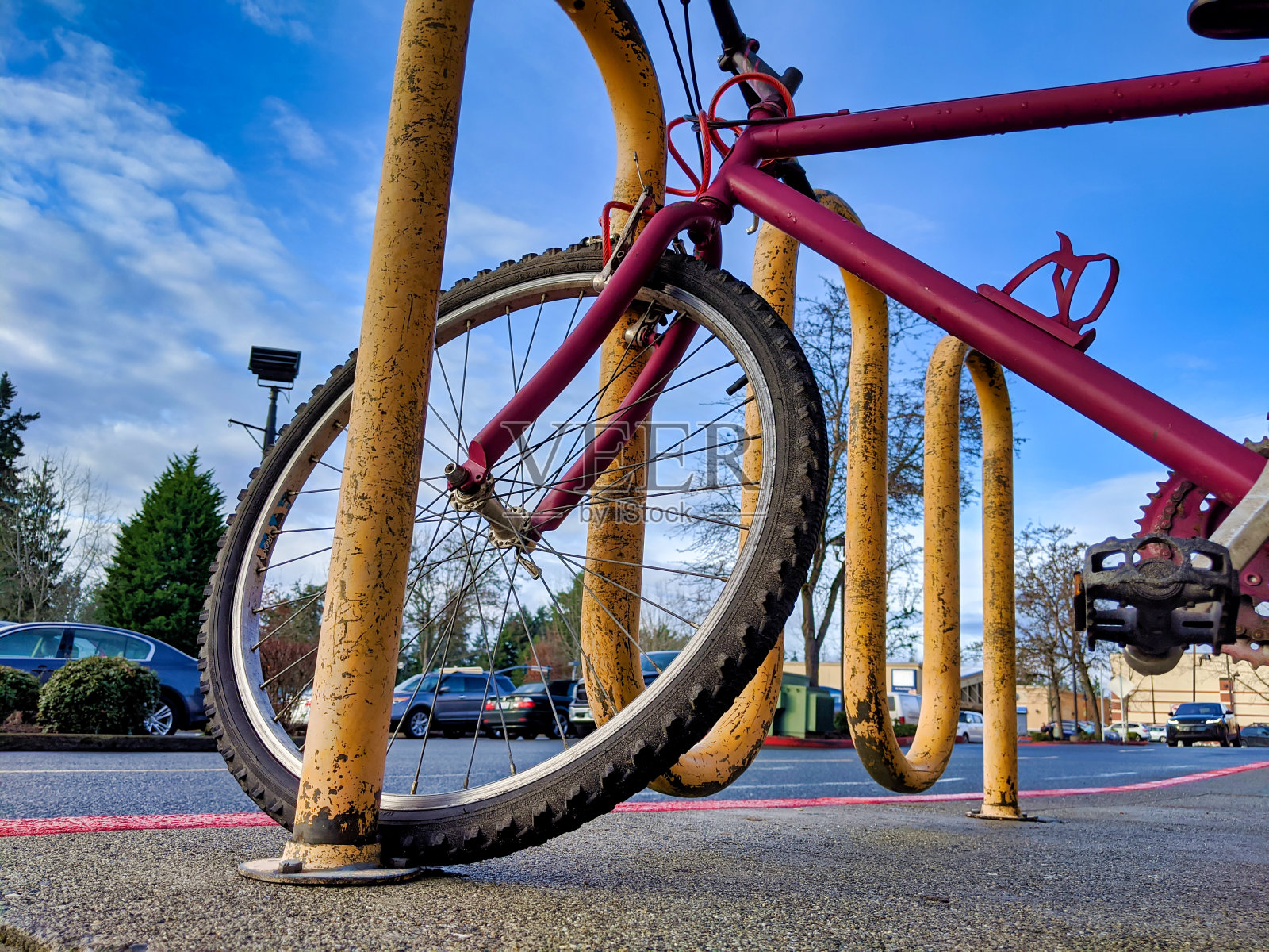 一辆锁在户外破旧自行车架上的红色自行车照片摄影图片