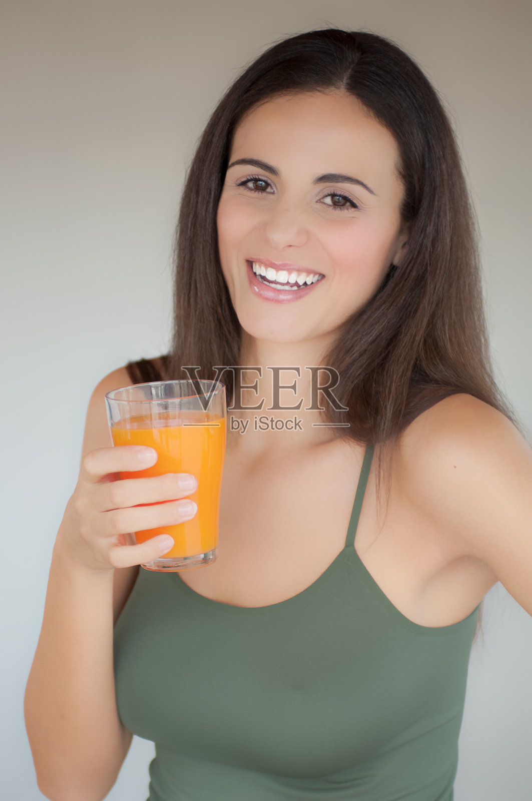 一个年轻女子拿着一杯橙汁笑了照片摄影图片