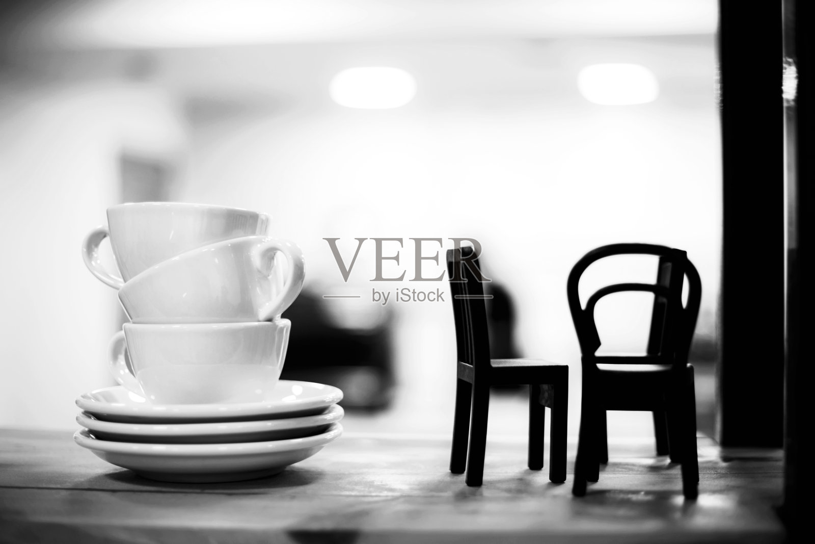 咖啡馆架子上一堆咖啡杯和小椅子。照片摄影图片