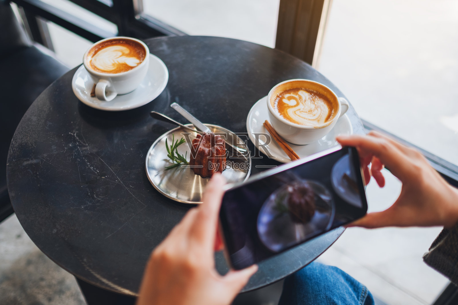 一个女人在吃咖啡和小吃前用手机拍照照片摄影图片